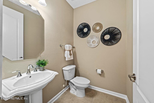 bathroom featuring tile patterned flooring, toilet, a textured ceiling, and sink