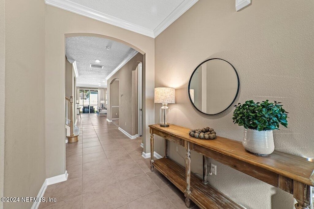 hallway featuring ornamental molding, a textured ceiling, and light tile patterned flooring