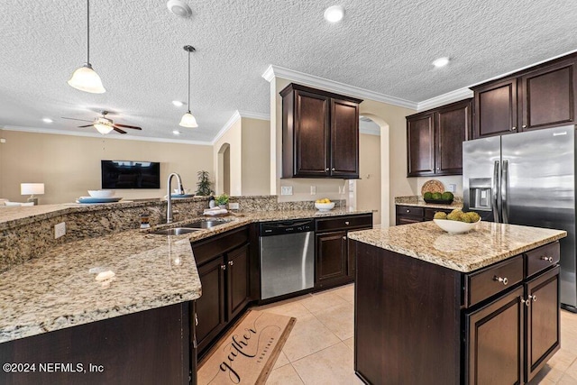 kitchen with a textured ceiling, decorative light fixtures, a center island, stainless steel appliances, and ceiling fan