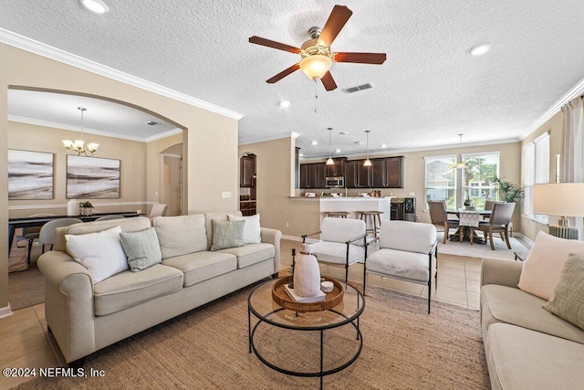 living room with ceiling fan with notable chandelier, a textured ceiling, ornamental molding, and light tile patterned floors