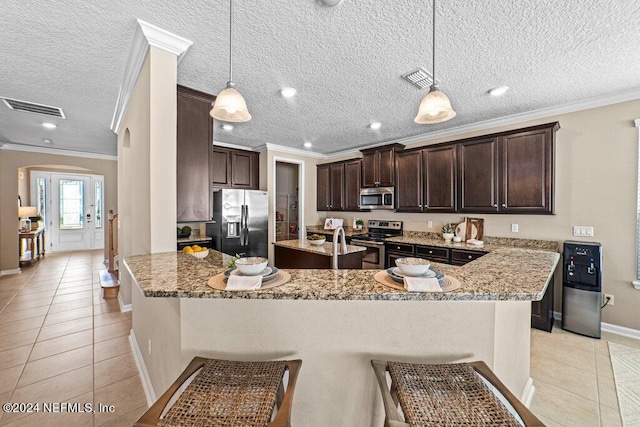 kitchen featuring a textured ceiling, pendant lighting, stainless steel appliances, ornamental molding, and light stone counters