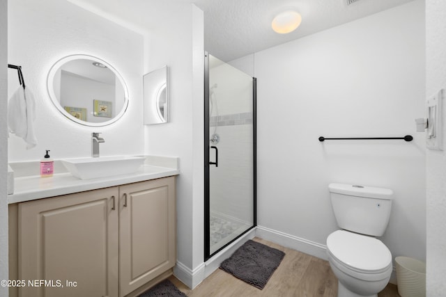 bathroom with an enclosed shower, vanity, a textured ceiling, hardwood / wood-style floors, and toilet