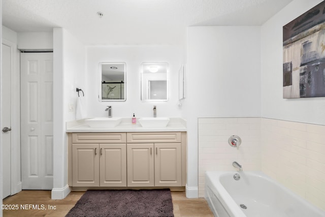 bathroom with a textured ceiling, vanity, a bath, and hardwood / wood-style floors