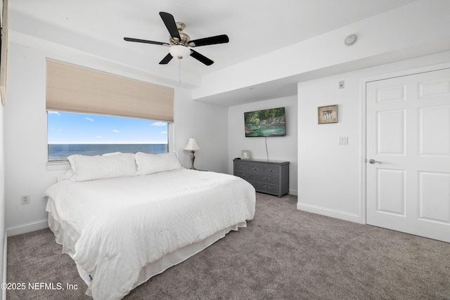 carpeted bedroom with ceiling fan and a water view