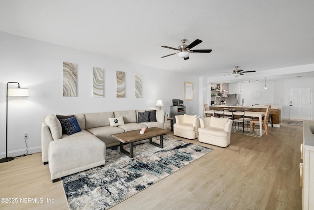 living room featuring ceiling fan and light hardwood / wood-style flooring