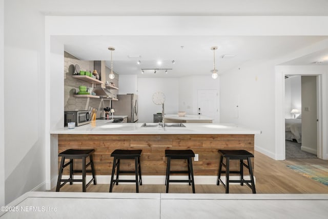 kitchen featuring pendant lighting, kitchen peninsula, a breakfast bar area, and stainless steel appliances