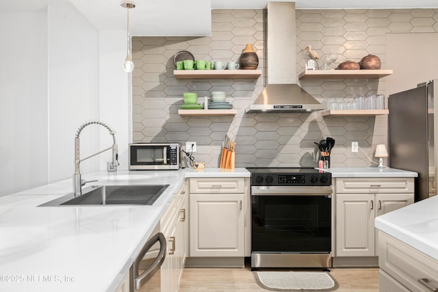 kitchen featuring backsplash, sink, wall chimney exhaust hood, decorative light fixtures, and stainless steel appliances