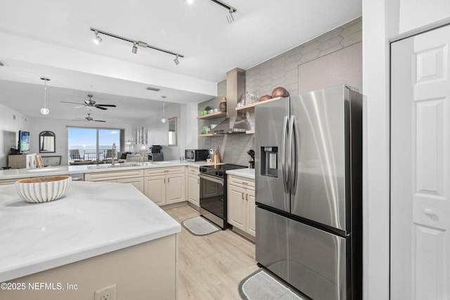 kitchen featuring appliances with stainless steel finishes, tasteful backsplash, wall chimney exhaust hood, sink, and light hardwood / wood-style floors