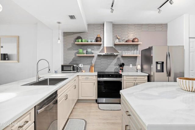 kitchen featuring backsplash, stainless steel appliances, sink, wall chimney range hood, and decorative light fixtures