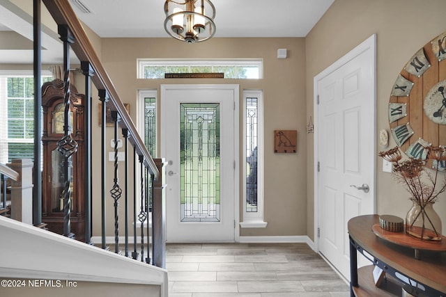 entryway with a wealth of natural light, a notable chandelier, and light hardwood / wood-style floors