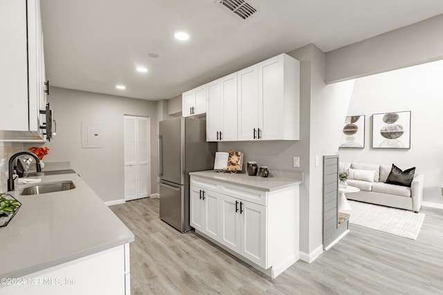 9360 Craven Rd Unit 504, Jacksonville, FL 32257 - kitchen featuring a sink, freestanding refrigerator, white cabinetry, light wood-type flooring, and visible vents