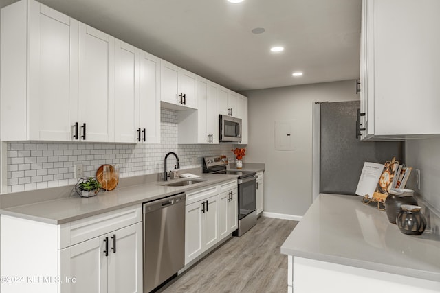 9360 Craven Rd Unit 504, Jacksonville, FL 32257 - kitchen featuring light wood-style flooring, tasteful backsplash, appliances with stainless steel finishes, white cabinetry, and a sink