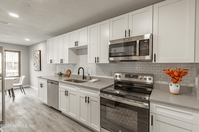 kitchen with appliances with stainless steel finishes, white cabinetry, and sink