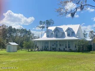 view of front of home featuring a front yard, a shed, and a porch