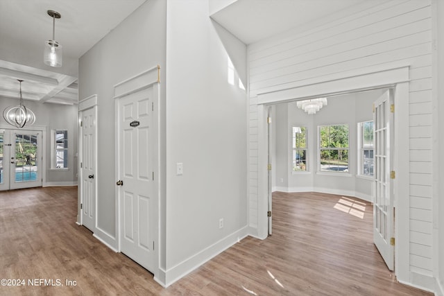 corridor with french doors, beam ceiling, coffered ceiling, and light wood-type flooring