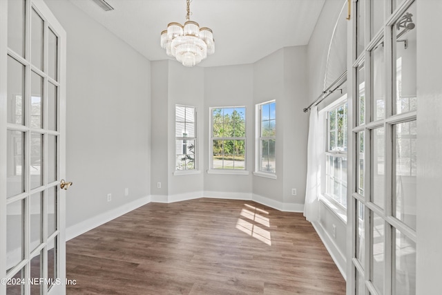 spare room featuring a notable chandelier and hardwood / wood-style flooring