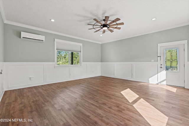 empty room with crown molding, wood-type flooring, a wall unit AC, and ceiling fan