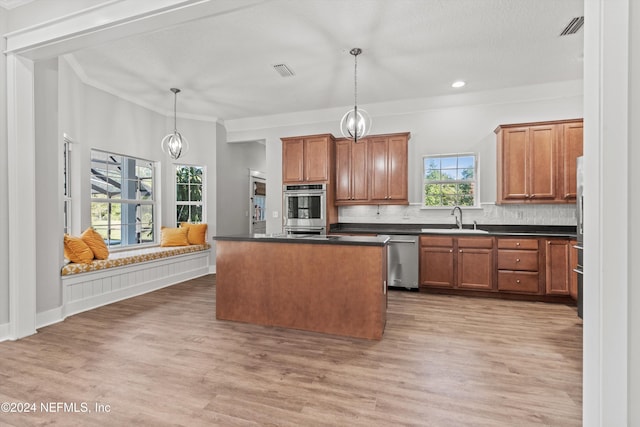 kitchen with hardwood / wood-style floors, a kitchen island, ornamental molding, decorative light fixtures, and stainless steel appliances