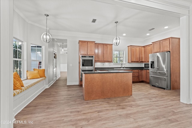 kitchen with a kitchen island, stainless steel appliances, crown molding, decorative light fixtures, and light wood-type flooring