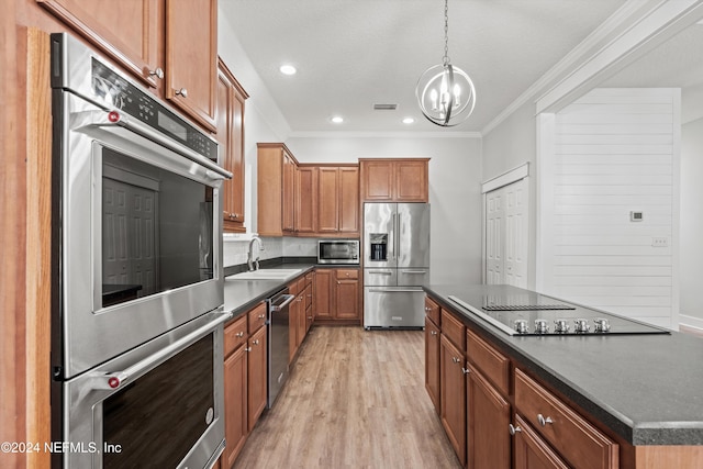 kitchen featuring ornamental molding, sink, pendant lighting, appliances with stainless steel finishes, and light hardwood / wood-style floors