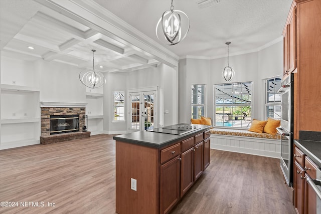 kitchen with black electric stovetop, hanging light fixtures, coffered ceiling, and plenty of natural light