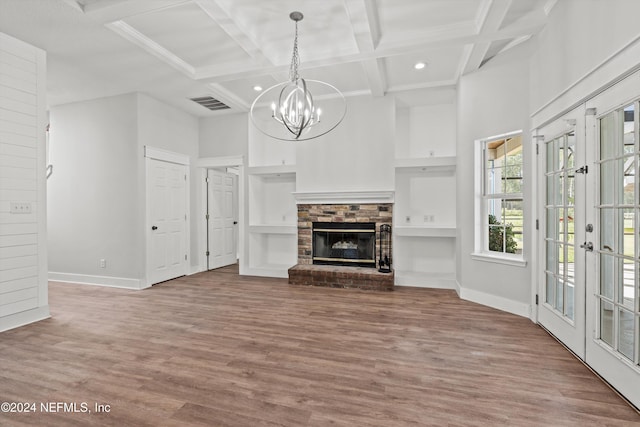 unfurnished living room featuring french doors, a stone fireplace, coffered ceiling, beamed ceiling, and hardwood / wood-style flooring