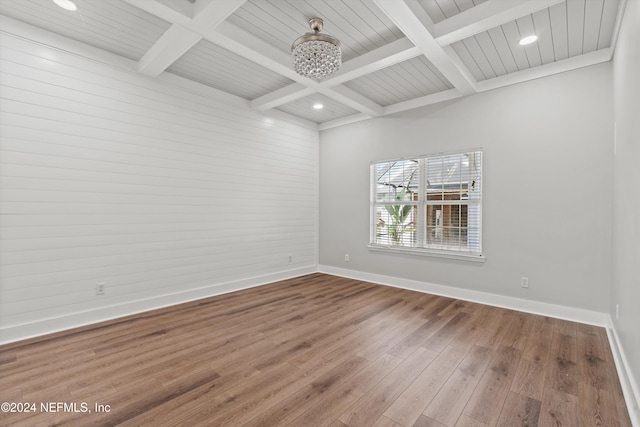 empty room featuring beamed ceiling, a chandelier, wood-type flooring, and coffered ceiling