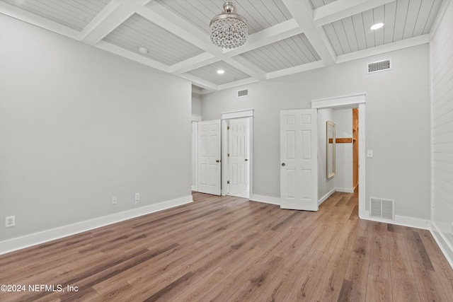 unfurnished bedroom featuring an inviting chandelier, light hardwood / wood-style flooring, beamed ceiling, and coffered ceiling