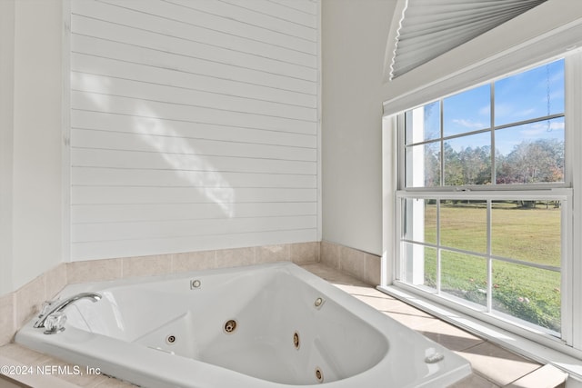 bathroom featuring a wealth of natural light and tiled bath