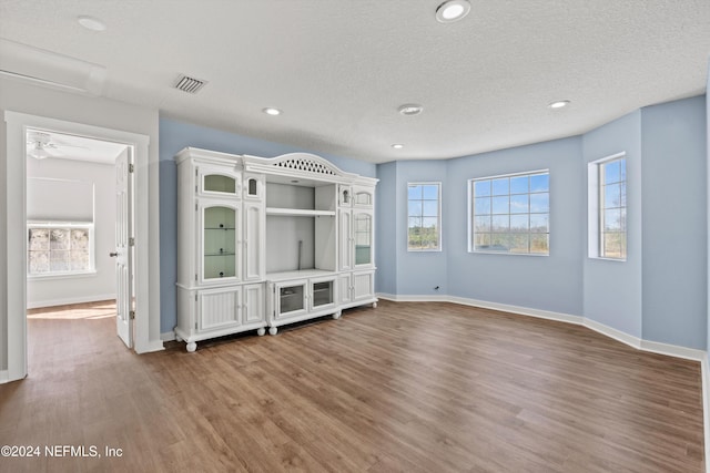 unfurnished living room with ceiling fan, hardwood / wood-style flooring, and a textured ceiling