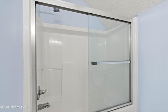 bathroom featuring a shower with door and a textured ceiling