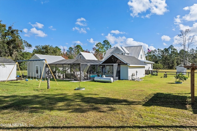 back of house with a shed, glass enclosure, a yard, and a pool