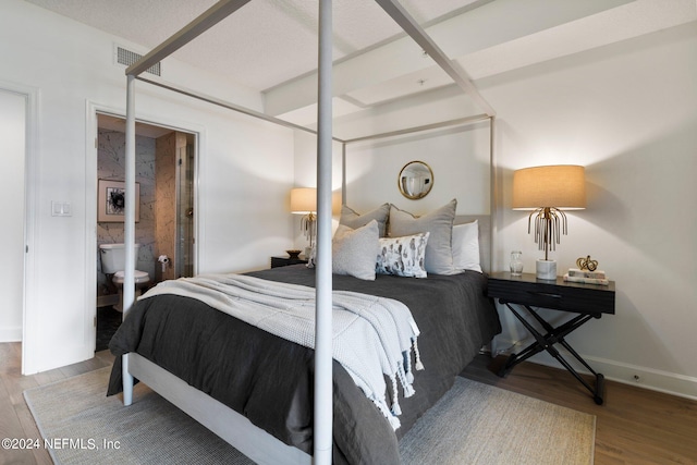 bedroom featuring connected bathroom and light hardwood / wood-style flooring