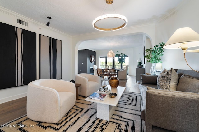 living room with a textured ceiling, ornamental molding, and hardwood / wood-style floors