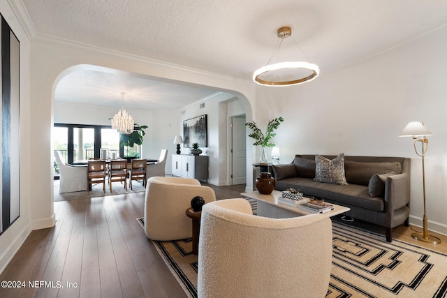 living room with hardwood / wood-style flooring, crown molding, arched walkways, and a textured ceiling