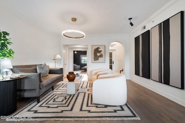 living area with arched walkways, crown molding, visible vents, a textured ceiling, and wood finished floors