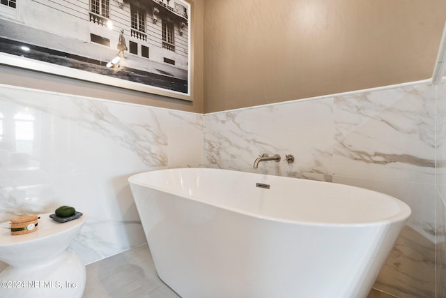 bathroom with tile walls, tile patterned flooring, and a washtub