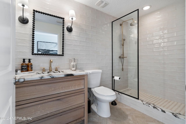 bathroom with tiled shower, vanity, toilet, and a textured ceiling