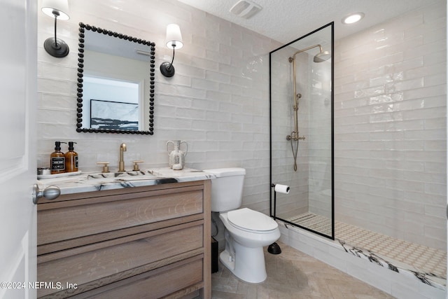 full bath featuring a textured ceiling, toilet, vanity, visible vents, and a tile shower