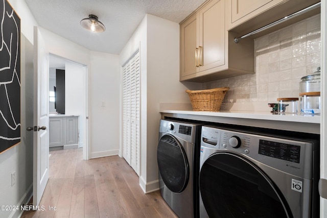 laundry room featuring a textured ceiling, cabinets, washer and clothes dryer, and light hardwood / wood-style flooring