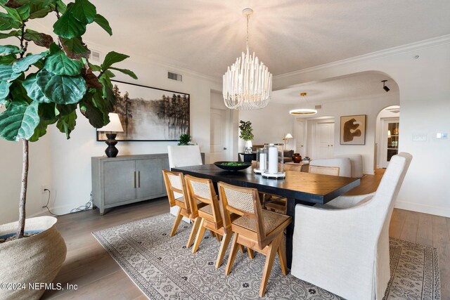 dining space featuring ornamental molding, hardwood / wood-style flooring, and a notable chandelier