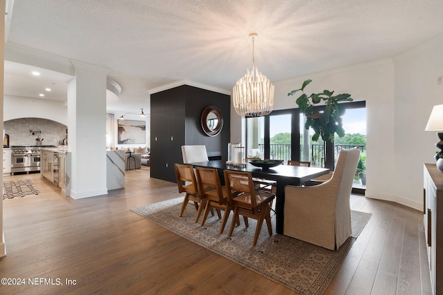 dining space with crown molding, a textured ceiling, a chandelier, and dark hardwood / wood-style floors