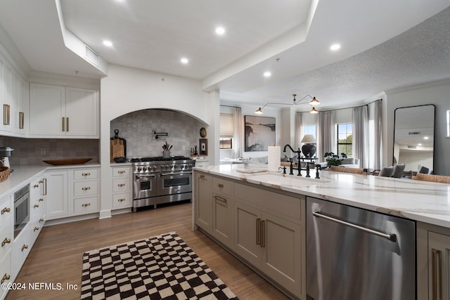 kitchen featuring hardwood / wood-style floors, light stone counters, stainless steel appliances, sink, and a textured ceiling