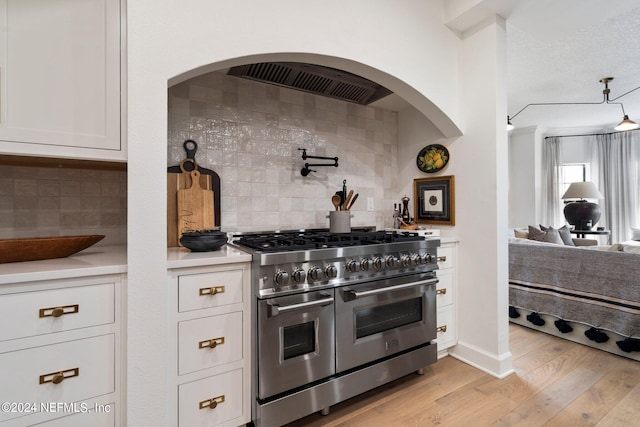 kitchen featuring light wood-type flooring, backsplash, white cabinetry, and double oven range