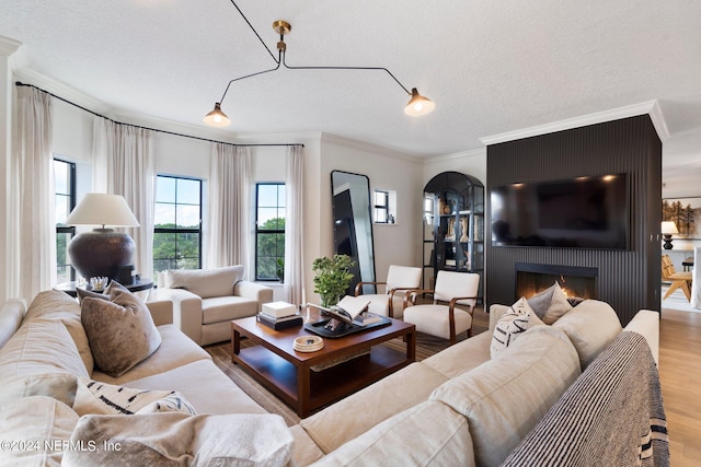 living room with a fireplace, a textured ceiling, light hardwood / wood-style flooring, and ornamental molding