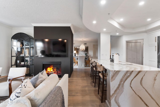 living room featuring a textured ceiling, dark hardwood / wood-style flooring, a large fireplace, ornamental molding, and sink