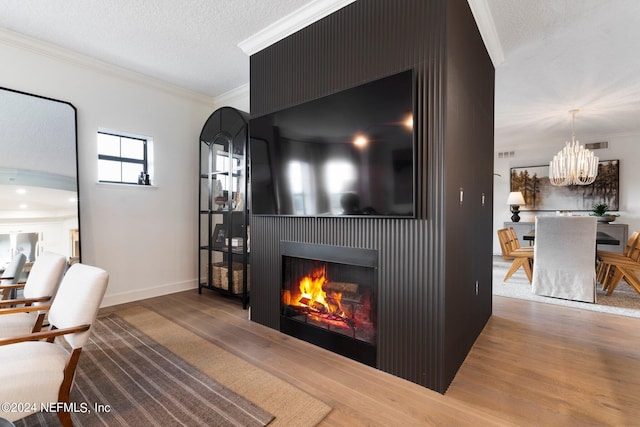 living room featuring crown molding, a textured ceiling, wood finished floors, a warm lit fireplace, and baseboards