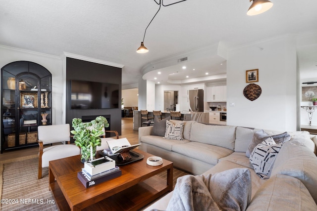 living room with crown molding, a textured ceiling, and wood-type flooring