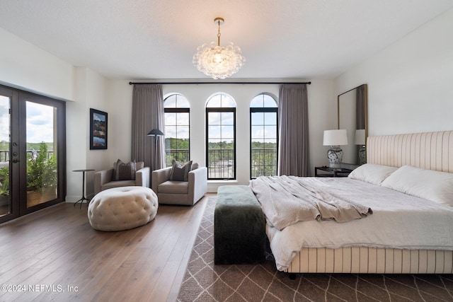 bedroom featuring french doors, a chandelier, access to exterior, and dark hardwood / wood-style floors