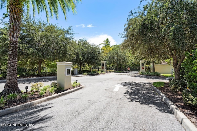 view of road featuring a gate, a gated entry, and curbs